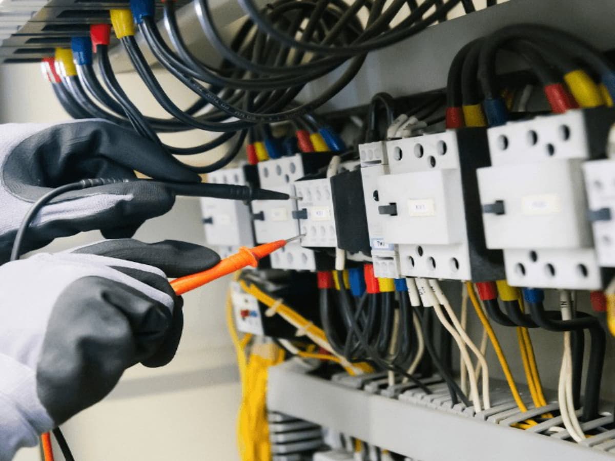 Manos cableando contactores en un armario